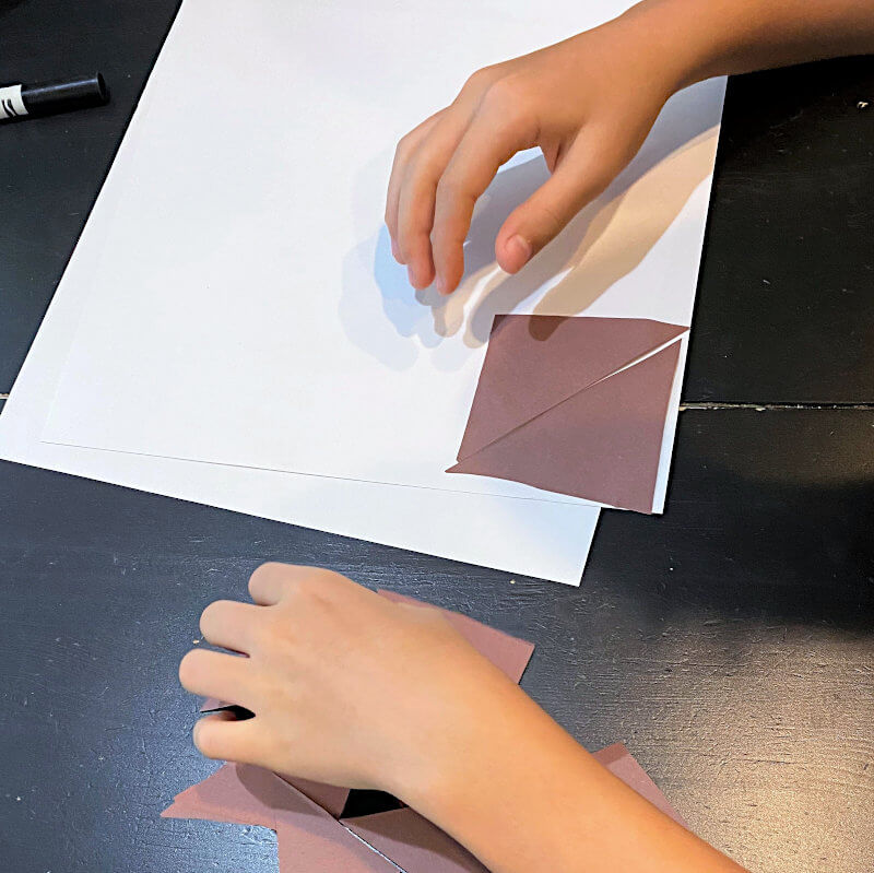child's hands arranging brown triangles to make an art project for Perfect Square picture book