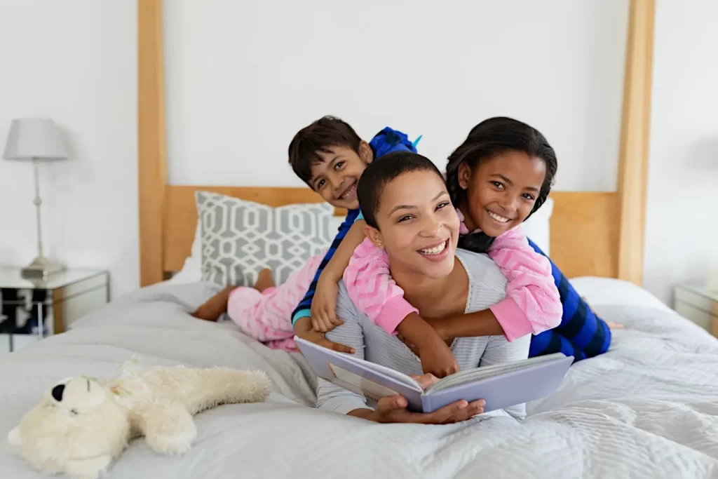 mom and kids piled on the bed with a picture book - books to tell kids I love you